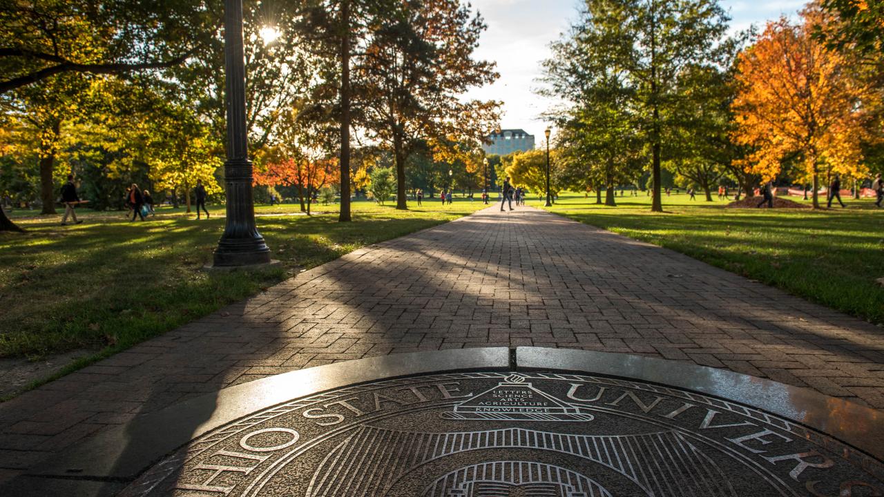 Seal on the oval in autumn looking toward Thompson Library
